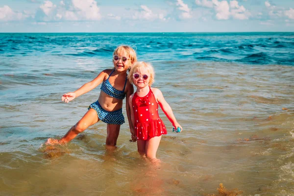 Счастливые симпатичные девчонки играют с водой на пляже — стоковое фото