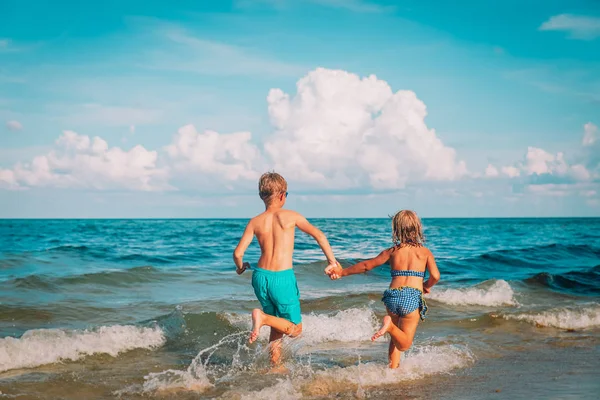 Mutlu çocuk ve kız plajda koşuyorlar. — Stok fotoğraf