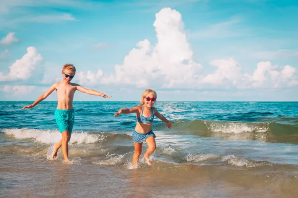 Gelukkig jongen en meisje run spelen op het strand — Stockfoto