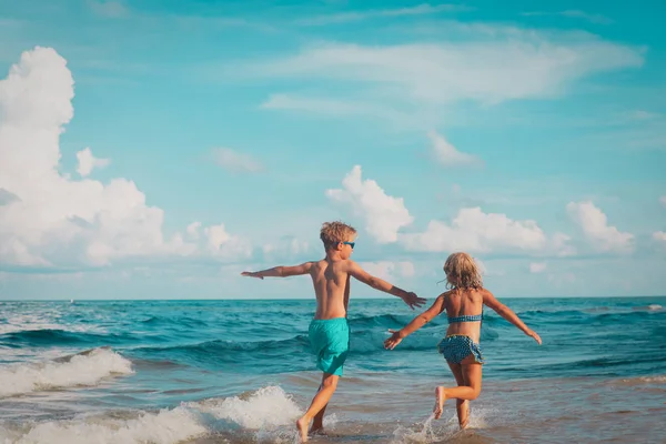 Gelukkig jongen en meisje run spelen op het strand — Stockfoto