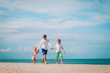 mutlu baba ve iki çocuk sahilde yürüyüş