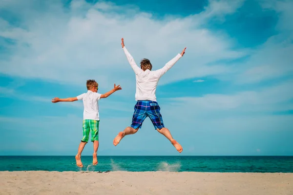 Vader en zoon have fun springen op tropisch strand — Stockfoto
