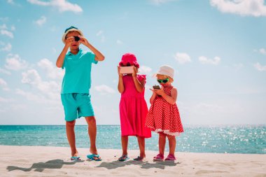 Sahilde cep telefonu ve kamera ile fotoğraf veya video yapan çocuklar