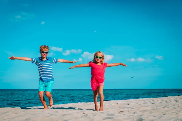 Feliz lindo chico y chica ejecutar jugar en la playa —  Fotos de Stock