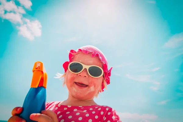 Cute little girl with sunblock cream on beach — Stock Photo, Image