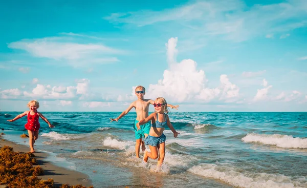 Niños felices - niño y niñas - correr jugar en la playa —  Fotos de Stock