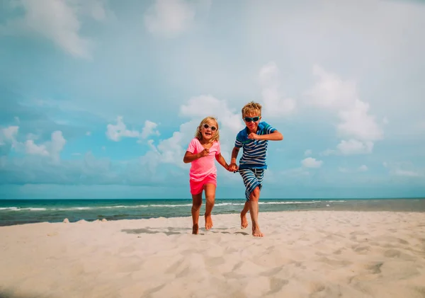 Menino bonito feliz e menina correndo na praia — Fotografia de Stock