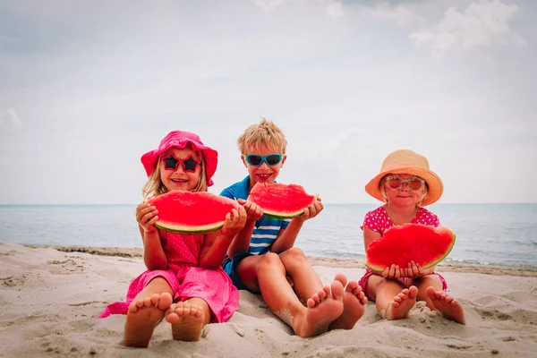 Счастливые милые дети едят арбуз на пляже — стоковое фото