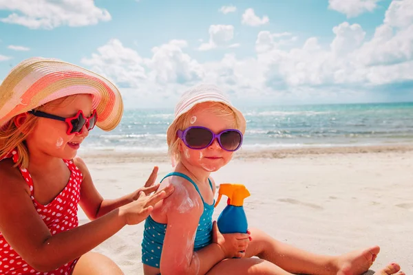 Proteção solar, meninas bonitos com creme solar na praia — Fotografia de Stock
