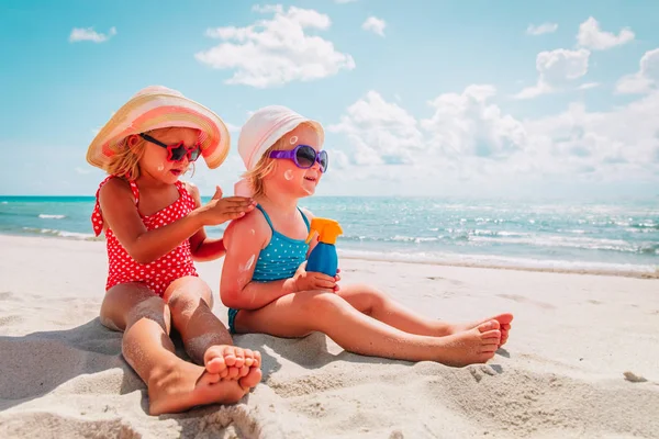 Proteção solar, meninas bonitos com creme solar na praia — Fotografia de Stock