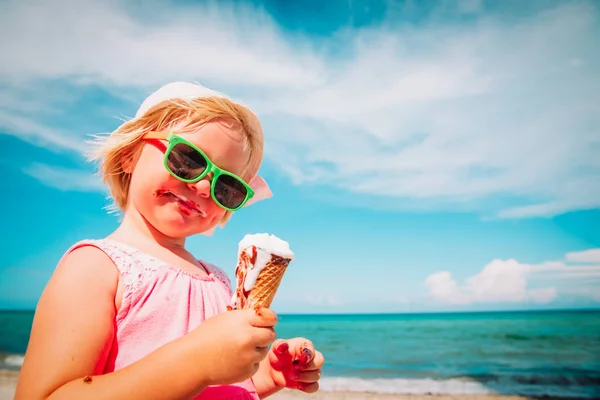 Heureuse petite fille mignonne manger de la crème glacée sur la plage — Photo