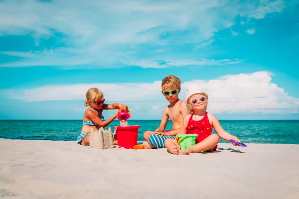 Milé děti-chlapec a dívky-hrají s pískem na pláži — Stock fotografie