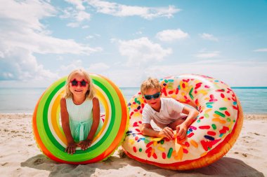 Sahilde floaties ile mutlu sevimli çocuk ve kız oynamak