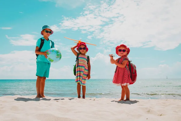 Niños viajan en la playa, niño y niñas con globo y avión de juguete en el mar —  Fotos de Stock