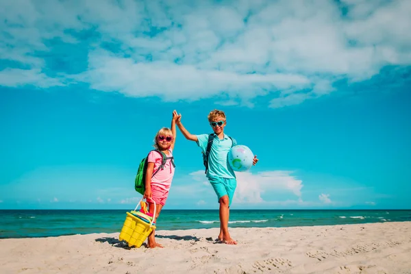 Niños viajan en la playa, niño y niñas con mochila, globo y juguetes en el mar —  Fotos de Stock