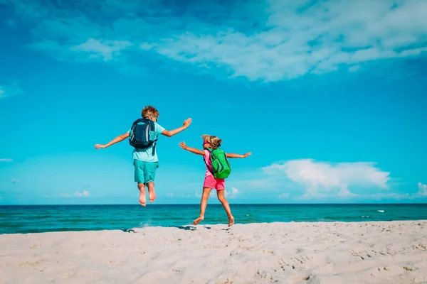 Glückliche Kinder mit Rucksäcken genießen das Reisen am Strand — Stockfoto