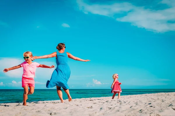 Glückliche Mutter mit kleinen Töchtern spielt am Strand — Stockfoto