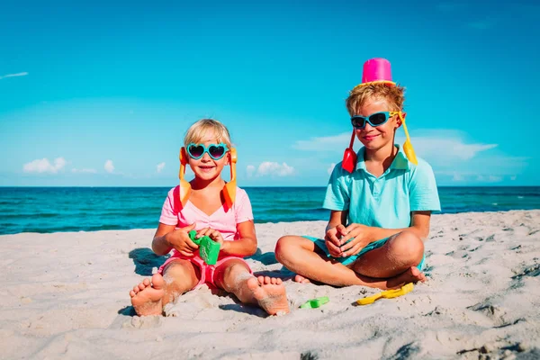 Счастливые девочка и мальчик играют с игрушками на пляже — стоковое фото