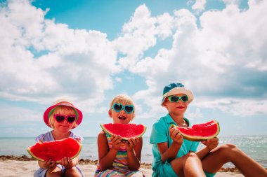 Sahilde karpuz yiyen mutlu sevimli çocuklar