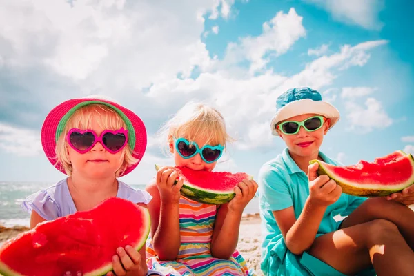 Sahilde karpuz yiyen mutlu sevimli çocuklar
