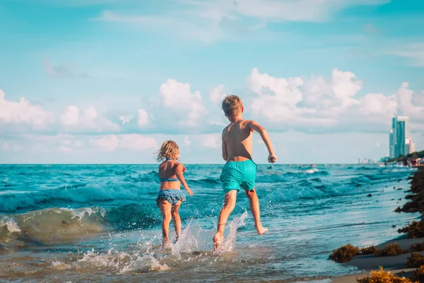 Gelukkig jongen en meisje run spelen op het strand — Stockfoto