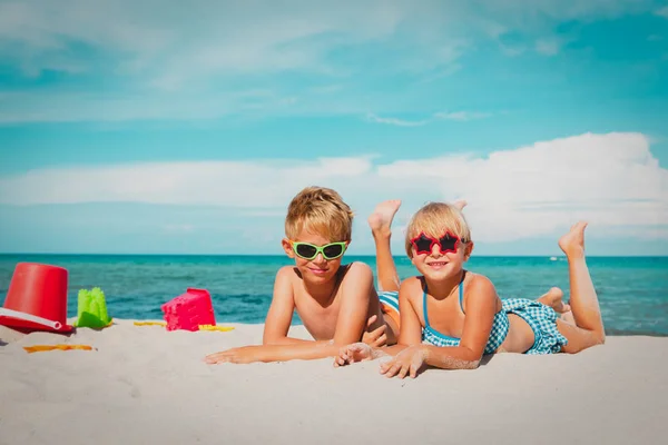 Leuke jongen en meisje spelen met zand op strand — Stockfoto