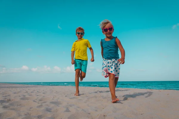 Счастливые мальчик и девочка бегут на пляже — стоковое фото