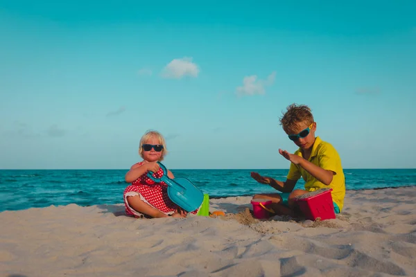 Lindo chico y chica jugar con arena en la playa —  Fotos de Stock