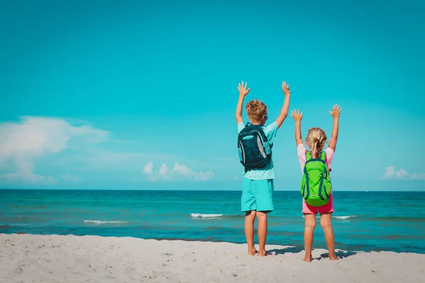 Glückliche Kinder mit Rucksäcken genießen das Reisen am Strand — Stockfoto