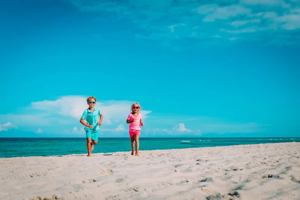 Счастливые мальчик и девочка бегут на пляже — стоковое фото