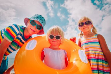 mutlu sevimli erkek ve kız plajda floaties ile oynamak