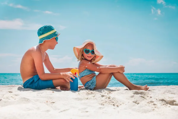 Proteção solar, menina bonito e menino com creme solar na praia — Fotografia de Stock