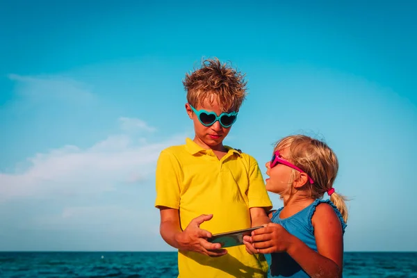 Carino ragazzo e ragazza guardando cellulare su spiaggia — Foto Stock