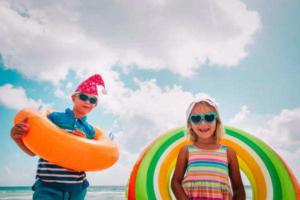 Crianças felizes menino e menina celebrando o Natal na praia — Fotografia de Stock