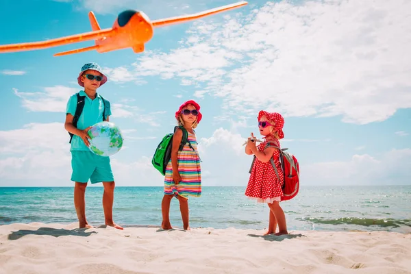 Kinder reisen am Strand, Jungen und Mädchen mit Globus, Spielzeugflugzeug und Fernglas — Stockfoto