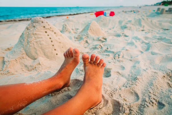 feet of boy play with sand on beach and toys on beach