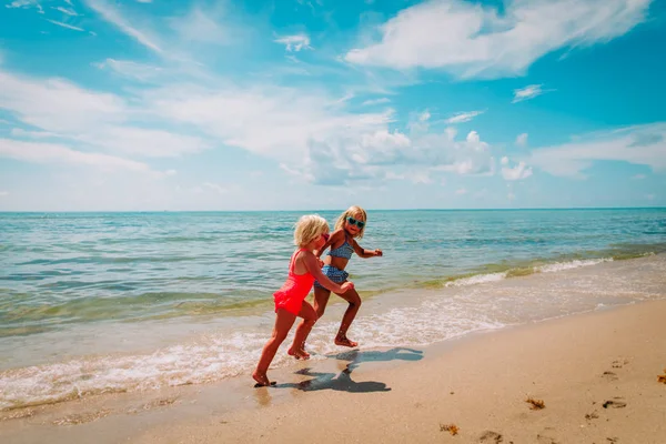 Happy Little Girls rennen en spelen op het strand — Stockfoto