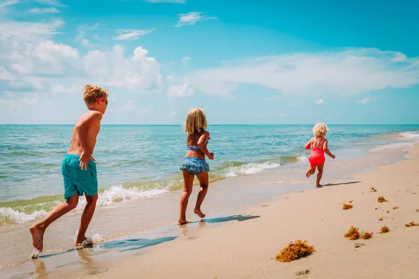 Счастливые дети мальчики и девочки бегают играть на пляже — стоковое фото