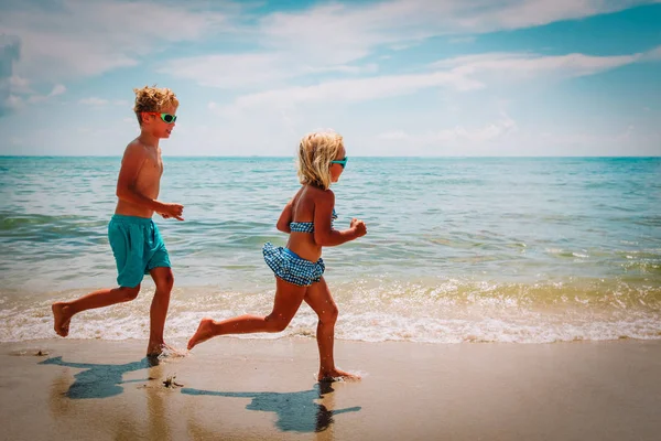 Gelukkig klein meisje en jongen lopen op het strand — Stockfoto