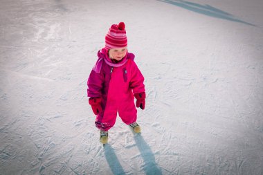 Mutlu küçük kız kışın paten kaymayı öğreniyor.