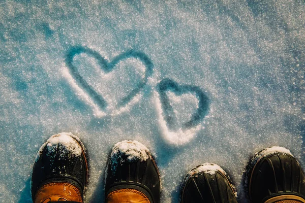 Conceito de inverno de amor - pernas em botas de neve e coração na natureza — Fotografia de Stock