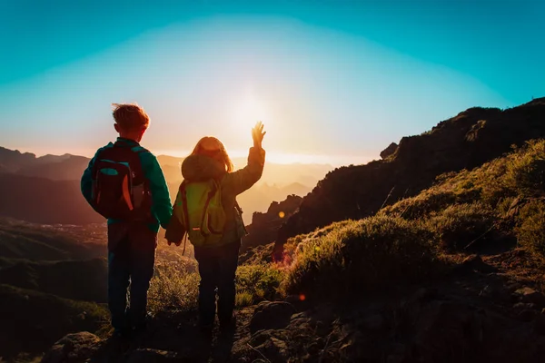 Счастливые мальчик и девочка путешествуют в горах на закате, дети любят походы — стоковое фото