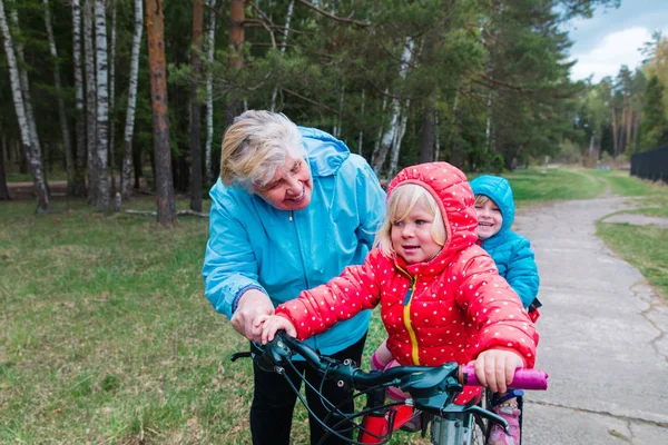 Avó ativa ensinando meninas a andar de bicicleta na natureza — Fotografia de Stock