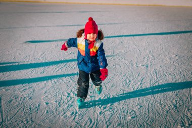 Mutlu küçük kız kışın paten kaymayı öğreniyor.