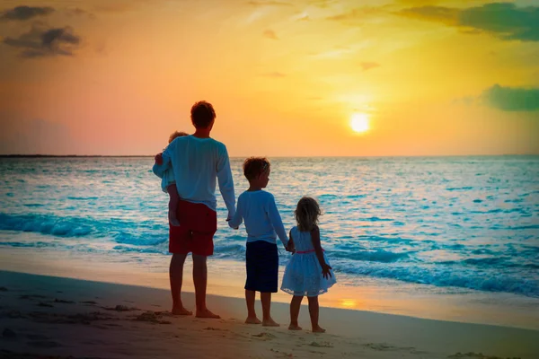 Padre con tres hijos caminando en la playa al atardecer —  Fotos de Stock