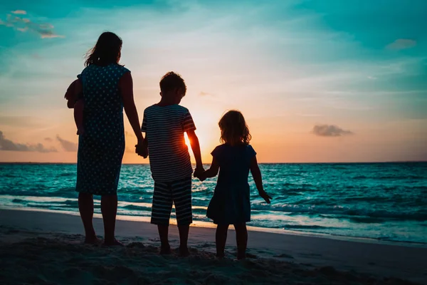 Μητέρα με τρία παιδιά το περπάτημα στην παραλία το ηλιοβασίλεμα — Φωτογραφία Αρχείου