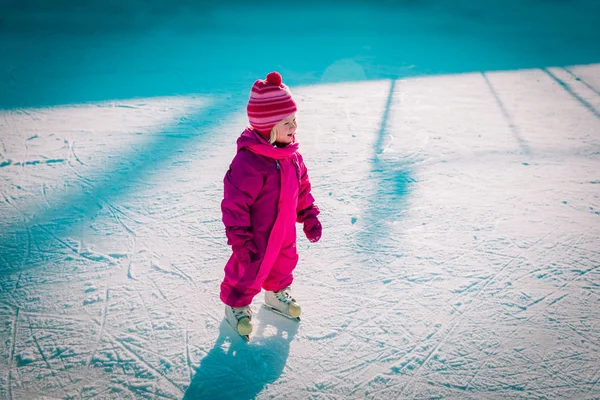 Mutlu küçük kız kışın paten kaymayı öğreniyor.