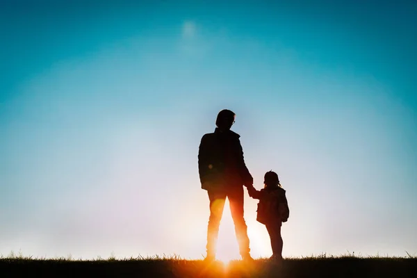 Отец с маленькой дочкой гуляют на закате — стоковое фото