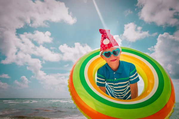 Felice ragazzo carino che celebra il Natale sulla spiaggia tropicale — Foto Stock