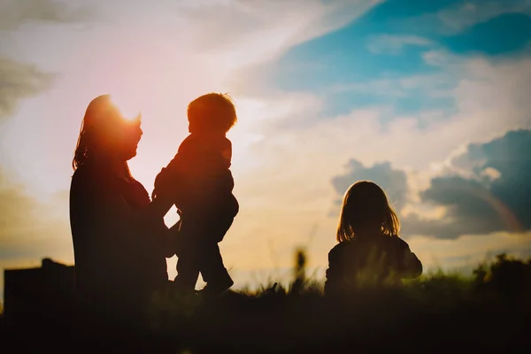 Felice madre e due figlie giocano nella natura al tramonto — Foto Stock